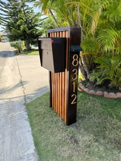 a mailbox sitting on the side of a road next to some trees and grass