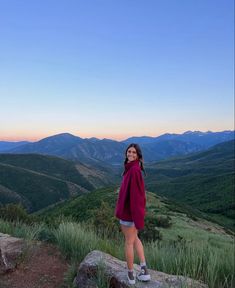 a woman standing on top of a rock in the mountains