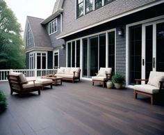 an outdoor deck with chairs and potted plants in front of the house's windows