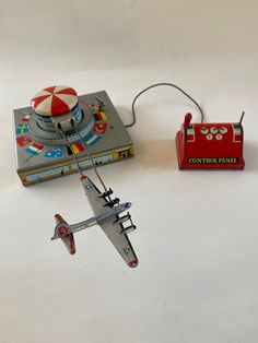 a toy airplane is sitting next to a box with a game on it and an object in the background