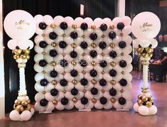 balloons are arranged in the shape of an arch with gold, white and black decorations