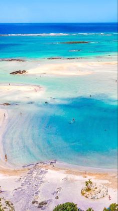 an aerial view of the beach and ocean with people swimming in the water, on a sunny day