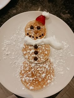 a plate topped with pancakes covered in powdered sugar and a snowman made out of them