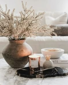 a table topped with a vase filled with flowers next to a candle and some books