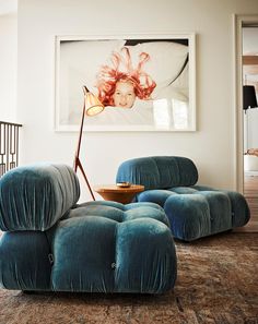 a living room filled with furniture and a painting on the wall above it's head