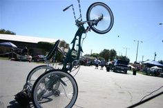 an upside down bicycle is parked in the middle of a parking lot with people walking around