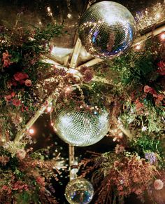 disco balls hanging from the ceiling in front of flowers and plants with lights on them