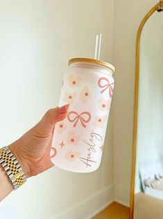 a hand holding a pink and white drink in front of a mirror with the words happy new year on it