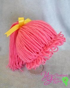 a pink ball of yarn with a yellow bow on the top is sitting on a white surface