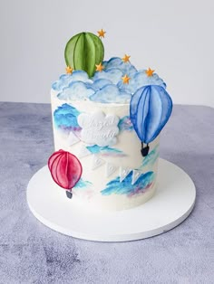 a birthday cake decorated with hot air balloons and stars in the sky on a white plate