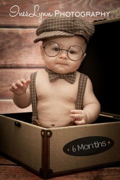 a baby wearing glasses and a hat sitting in a box with the words 6 months on it