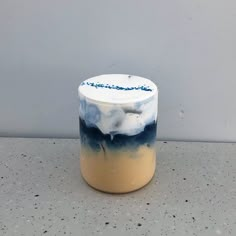 a white and blue vase sitting on top of a gray counter next to a wall