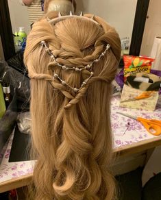 a woman with long blonde hair wearing a crown braid and pearls on it's head