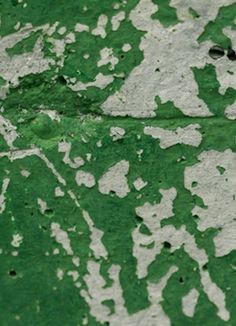 an old green and white wall with peeling paint