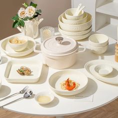 a white table topped with lots of plates and bowls