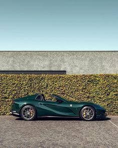 a green sports car parked in front of a wall