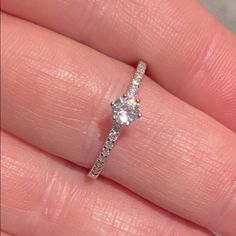 a woman's hand with a diamond ring on top of her finger and the bottom half of her wedding band