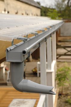 a metal gutter attached to the side of a building with wood planks on it