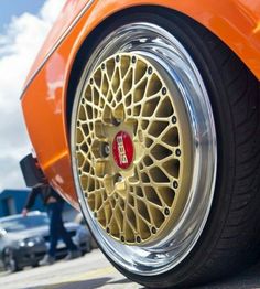 an orange sports car with gold rims parked in a parking lot