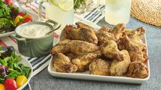 some chicken wings are on a plate next to a bowl of ranch dressing and salad