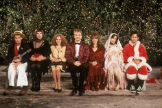 a group of people sitting next to each other in front of a christmas tree