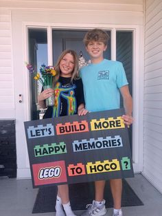 two people standing in front of a house holding a sign that says let's build more happy memories to hoco