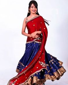 a woman in a red and blue lehenga posing for the camera with her hands on her hips