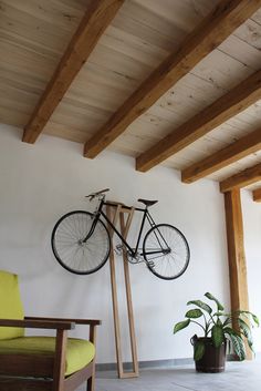 a bicycle mounted to the wall in a living room next to a chair and potted plant