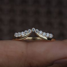 a hand holding a gold ring with three diamonds on it's side and the middle one is half closed