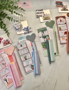 several stationery items are laid out on a marble surface with greenery in the background