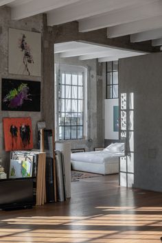 a living room filled with lots of furniture and paintings on the wall next to a window