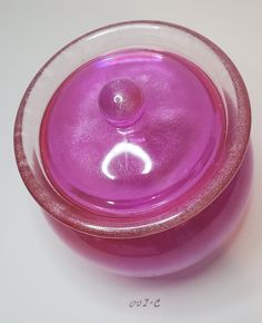 a pink glass bowl with a white circle on the top and bottom, sitting on a table