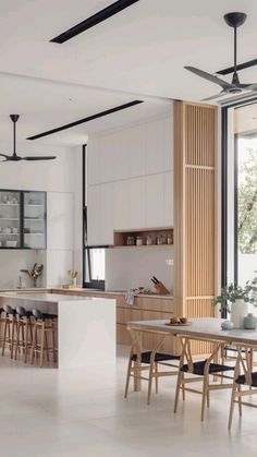 an open concept kitchen and dining area with white tile flooring, black ceiling fans and wooden accents