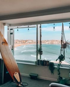 a surfboard leaning against a window overlooking the ocean