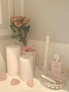 some candles and flowers in a white bathroom