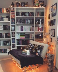 a room with bookshelves and lights in the corner, all lit up by fairy lights