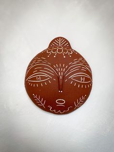 a brown clock with white designs on it's face is shown in front of a white background