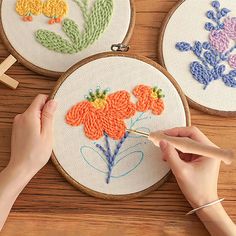 someone is working on some embroidery work with scissors and needleing needles, which are sitting on a wooden surface