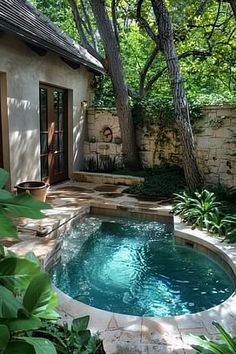 a small swimming pool in the middle of a yard with trees and plants around it