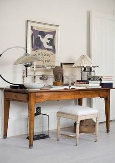 a wooden desk topped with a lamp next to a white chair