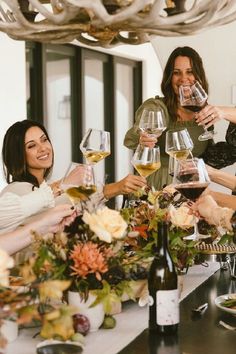 four women toasting with wine glasses on a table