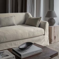 a white couch sitting next to a wooden table with a lamp on top of it