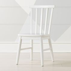 a white wooden chair sitting on top of a hard wood floor next to a wall