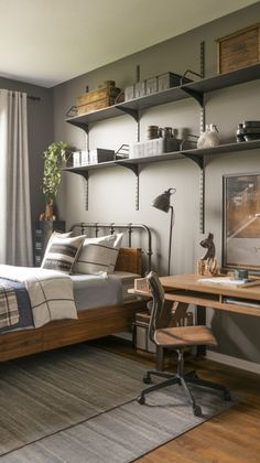 a bedroom with a bed, desk and shelves on the wall next to a window