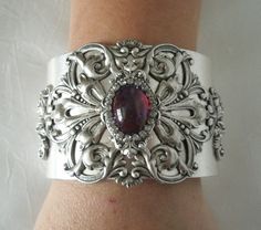 "This beautiful silver plated cuff bracelet has a silver plated floral design and a glass dragon's breath fire opal setting with rhinestone accents. 2\" wide. Adjustable." Elegant Silver Cuff Bracelet With Jewels, Ornate Antique Silver Cuff Bracelet For Weddings, Victorian Silver Cuff Bracelet With Intricate Design, Ornate Silver Jeweled Bracelets, Silver Victorian Cuff Bracelet With Intricate Design, Ornate Silver Bracelet With Jewels, Ornate Silver Bracelets With Jewels, Vintage Silver Cuff Bracelet For Party, Victorian Silver Bracelets With Jewels