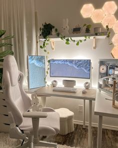 a computer desk with two monitors and a keyboard on it in front of a plant