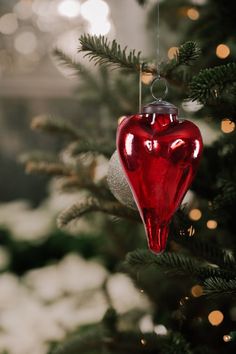 a red heart ornament hanging from a christmas tree