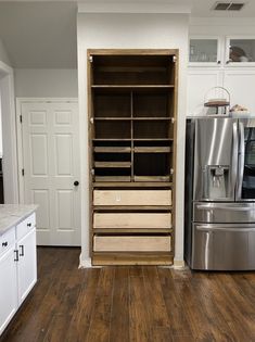 a kitchen with white cabinets and stainless steel appliances in the center, along with an open pantry