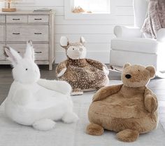 three stuffed animals sitting on the floor next to each other in a room with white walls