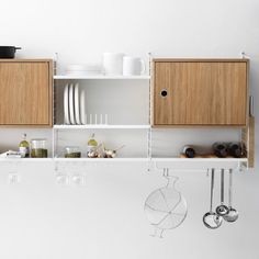 a kitchen with wooden cabinets and white counter tops, hanging utensils from the ceiling